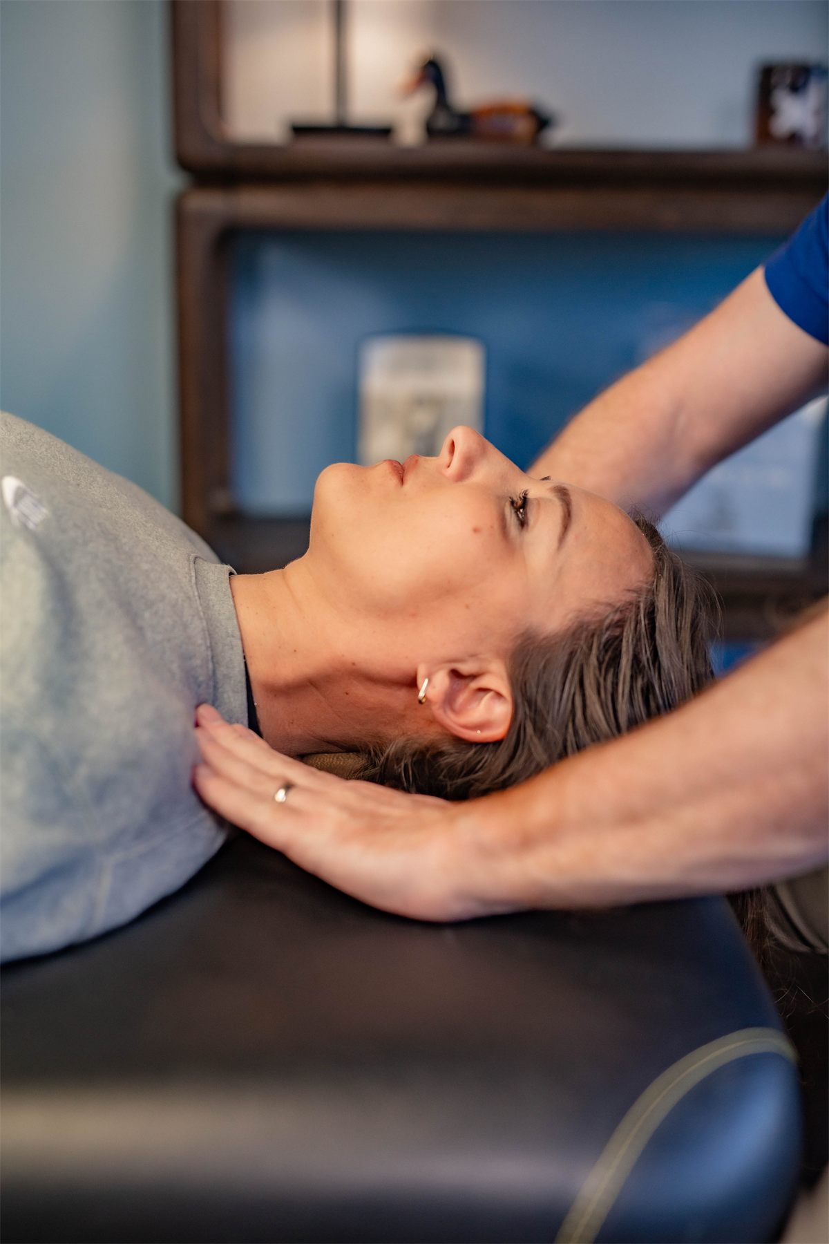 Close-up of a therapist's hands performing Fascial Counterstrain on a patient's neck